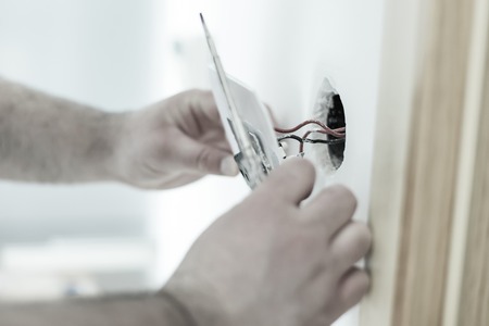 Man installing light switch after home renovationの写真素材