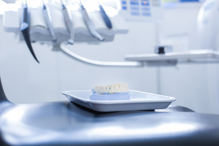 Dental plaster mold on dentist's chair with specialist tools, drills, handpieces and laser in the backgroundの写真素材