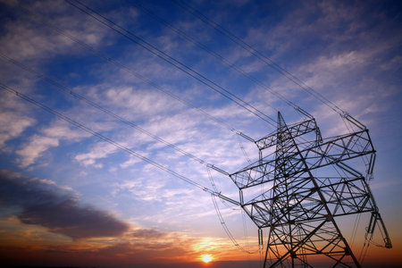 Pylon and power lines at sunset with nice sky and sun