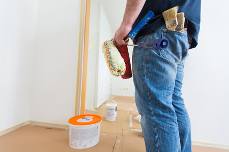 Man holding rollers and brushes while renovating homeの写真素材
