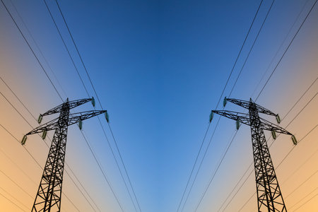 Electric power lines against blue and yellow skyの写真素材