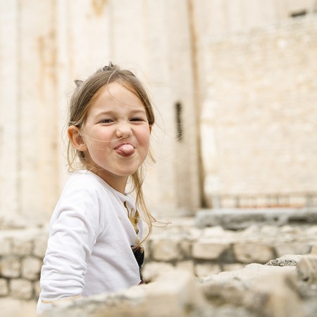 Playful and carefree cute little Caucasian girl making faces, looking at mum and dad.の写真素材