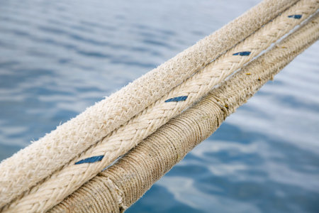 Heavy duty and weathered ropes, attached to the pier for secure docking of a ship. Maritime, nautical concept, background.の写真素材