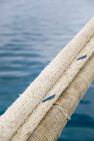 Heavy duty and weathered ropes, attached to the pier for secure docking of a ship. Maritime,...