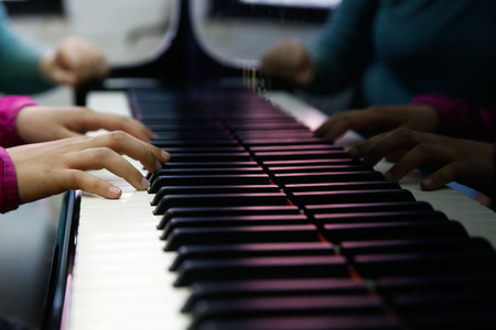 Teenager playing a piano, close-up on hands and keyboard. Rehearsal, school and discipline concept.の写真素材