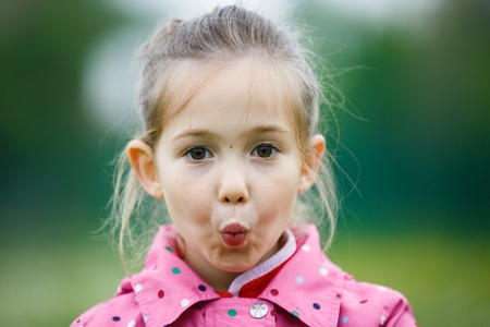 Little girl making faces for the camera on a hiking trip with her family. Disobedience, cheerful  behavior and carefree childhood concept.の写真素材