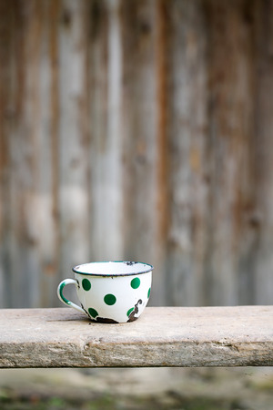 Charming vintage dotted metal cup, covered in decorated enamel, rusty on the edges. Home decoration, old times, retro kitchen concept.の写真素材