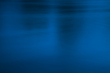 Deep and blurred, dark blue and black water surface, conceptual abstract background. Dark, sullen atmosphere, uneasiness, crime, fear, underground, and evil concept.の写真素材