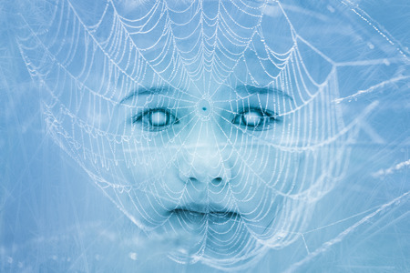 Spooky zombie child face covered in cobweb. Halloween, horror, gothic themes. Double exposure.の写真素材