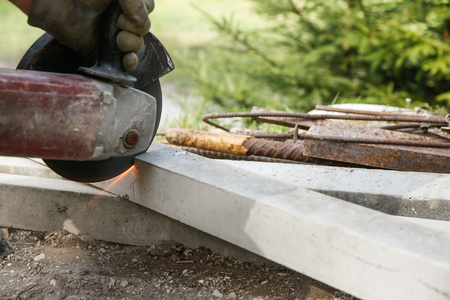 Construction worker cutting a reinforced concrete pillar for installation with professional machine. Construction business, do-it-yourself, dirty and dangerous work around the house concept.の写真素材