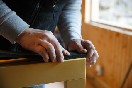 Worker preparing to install new three pane wooden windows in an old wooden house.の写真素材