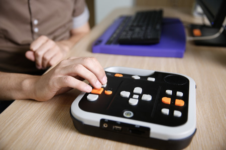 Blind person using audio book player for visually impaired, listening to audio book on his computer. Blindness aid, visual impairment, independent life concept.