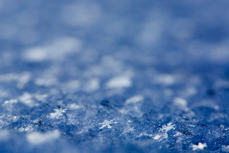 Snowflakes on a snow cover, closeup. Textured background with copy space, winter concept. の写真素材