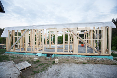 Frame of wooden house under construction, covered with tyvec home wrap. Building process,...