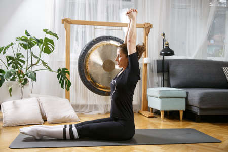 Fit active woman stretching, doing pilates and yoga fitness exercise in room at home. Home fitness. Healthy and sport lifestyle.の写真素材