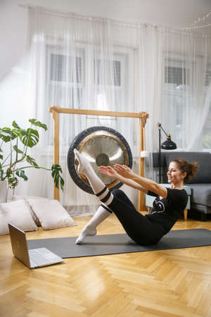 Pilates and yoga teacher giving private lessons using laptop during  virus epidemic. Working from home.の写真素材