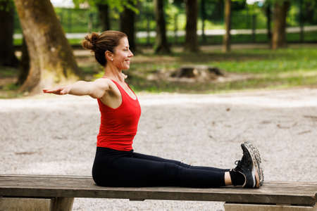 Woman working out before fitness training session in the park. Healthy young woman warming up outdoors.の写真素材