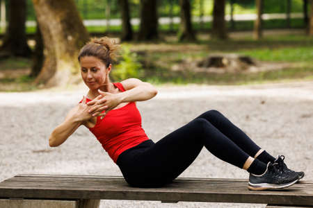 Woman working out before fitness training session in the park. Healthy young woman warming up outdoors.の写真素材