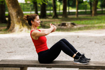 Woman working out before fitness training session in the park. Healthy young woman warming up outdoors.の写真素材