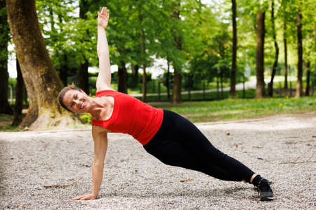 Woman working out before fitness training session in the park. Healthy young woman warming up outdoors.の写真素材