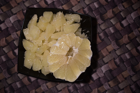 Sliced pomelo without skin on a black plateの写真素材