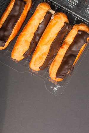 Eclairs with cream filling drenched in chocolate on a black the background.