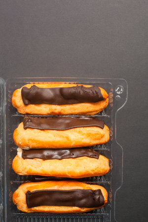 Eclairs with cream filling drenched in chocolate on a black the background.