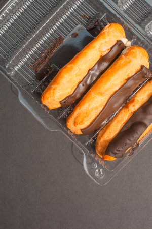 Eclairs with cream filling drenched in chocolate on a black the background.
