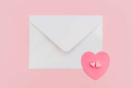 closed pearlescente envelope with paper heart on the pink background. Flat lay. top view. Romantic love letter for Valentine's day concept.の写真素材