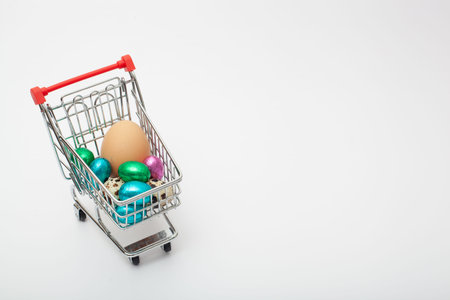different color and size eggs are in the grocery cart on the white background