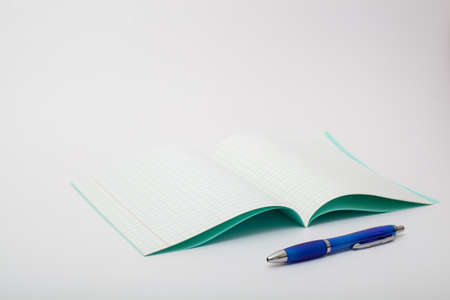 school supplies isolated on white background. photo on the topic of studying at school. notebook and a blue ballpoint pen on a white backgroundの写真素材