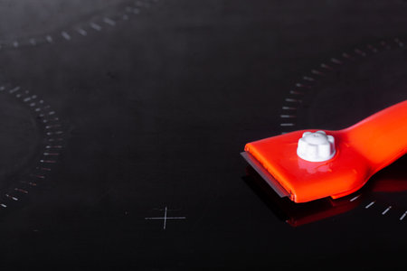 Scraper for cleaning glass ceramics against the background of a clean glass ceramic panel