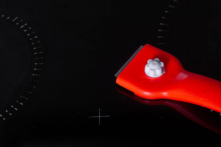 Scraper for cleaning glass ceramics against the background of a clean glass ceramic panel