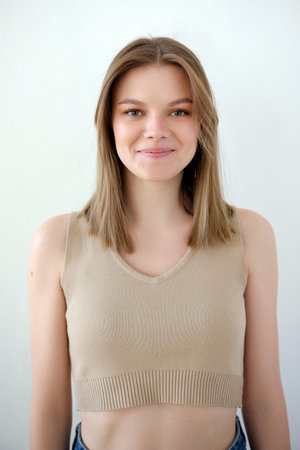 Young smiling girl model snap in beige top t-shirt front look portrait view on white background