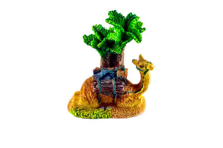 Statuette of a camel lying under a palm tree isolated on white backgroundの写真素材