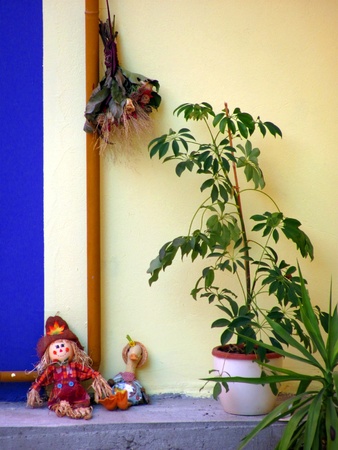 Homemade dolls resting in front of wall surounded with flowersの写真素材