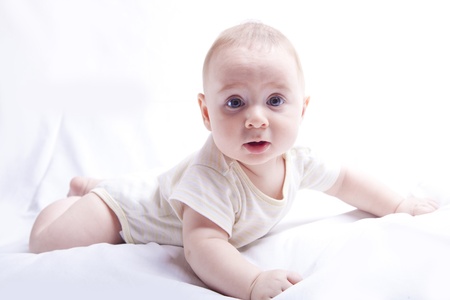 Baby boy looking surprised while laying on his tummy, on a white backgroundの写真素材