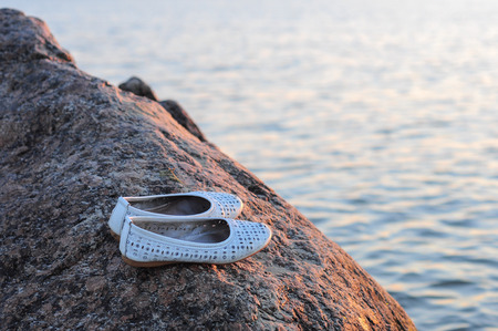 At summer sunset lady shoes are on a stoneの写真素材