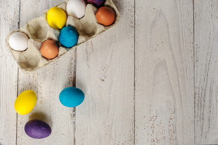 Colored easter eggs in carton on wooden white shabby backgroundの写真素材