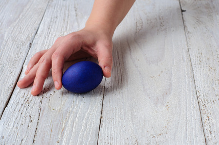 Colored easter eggs in hands on wooden white shabby backgroundの写真素材