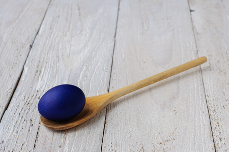 Colored easter eggs in spoon on wooden white shabby backgroundの写真素材