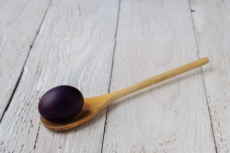 Colored easter eggs in spoon on wooden white shabby backgroundの写真素材