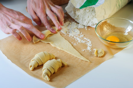 Croissants making on white table with flour and baking paperの写真素材
