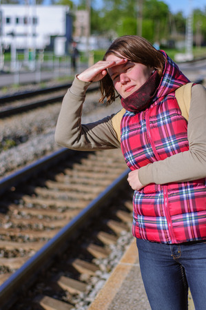 Girl with backpack waits train on train stationの写真素材