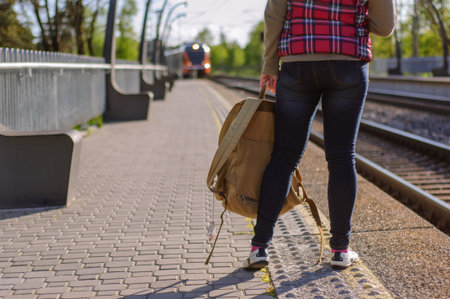 Legs of girl waiting train on train station with backpack
