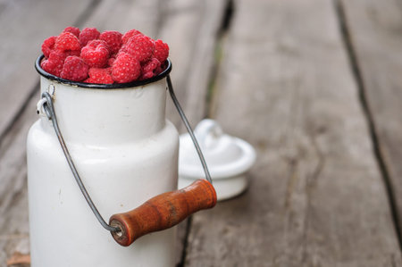 White can with fresh raspberry on old wooden background