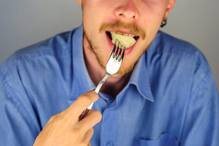 Young man in blue shirt eats dumplings with meatの写真素材