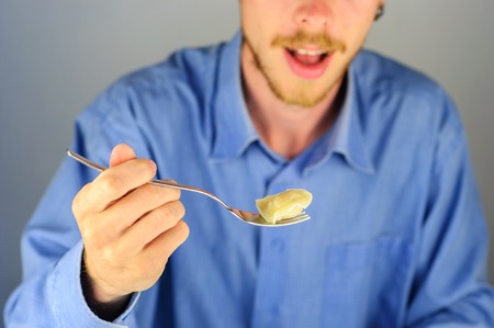 Young man in blue shirt eats dumplings with meatの写真素材