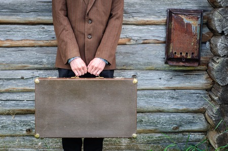 Man hipster with old vintage suitcase near old country houseの写真素材