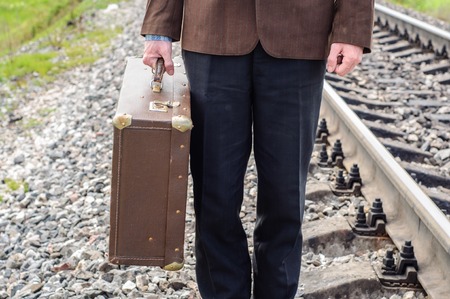 Man hipster with old vintage suitcase on railwaysの写真素材